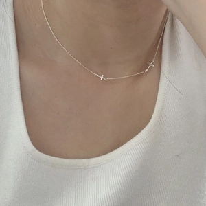 Close-up of minimalist S925 sterling silver thin necklace with tiny cross pendants