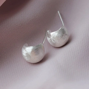 Vue macro de boucles d'oreilles minimalistes en argent S925 avec finition mate brossée fine