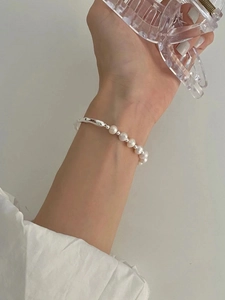 Gros plan d'un bracelet en argent S925 avec perles d'eau douce sur poignet délicat