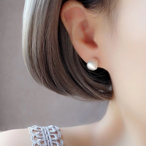 Gros plan de boucles d'oreilles courbes en argent S925 brossé mat sur une oreille