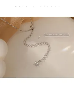Détail macro de l'extension de chaîne en argent avec un délicat pendentif fleur à pétales