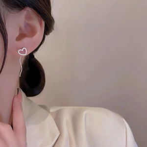 Close-up of S925 silver heart stud earrings with sparkling tassel fringe on a female model