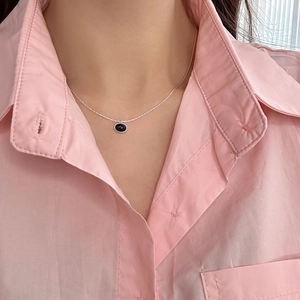Close-up of S925 silver necklace featuring an oval black onyx pendant on a model