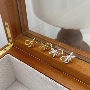Detail von goldenen und silbernen Schleifen-Ohrsteckern auf einer rustikalen Schmuckschatulle