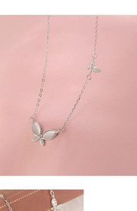 Macro detail of S925 silver butterfly necklace with opal wings and zircon accents