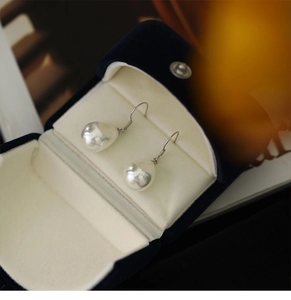 Macro shot of S925 sterling silver drop pearl earrings presented in a blue velvet gift box