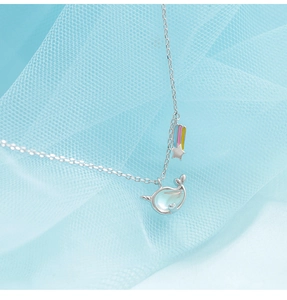 Makroaufnahme von Narwal-Anhänger mit buntem Regenbogen-Stern-Charm auf blauem Netzgewebe