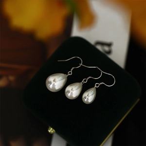 Three sizes of vintage teardrop pearl earrings on green velvet jewelry box