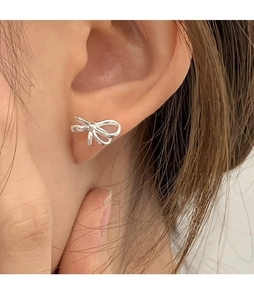 Nahaufnahme von minimalistischen Silberbogen-Ohrsteckern für einen zarten Look