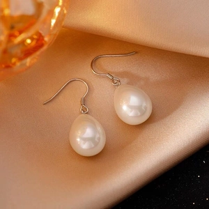 Close-up of S925 sterling silver hooks with drop pearls on champagne satin fabric