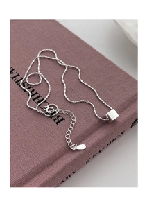 Macro detail of S925 sterling silver geometric cube pendant on a minimalist bead chain
