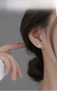 Gros plan de boucles d'oreilles fleurs en perles dorées portées par un mannequin