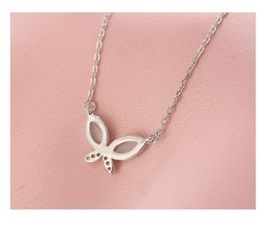Macro view of S925 silver butterfly pendant with zircon inlay on pink silk fabric