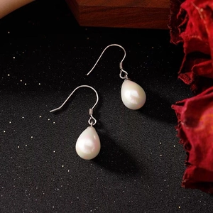 Macro shot of elegant S925 sterling silver waterdrop pearl earrings on dark background