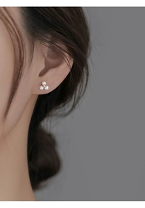 Gros plan de boucles d'oreilles trèfle en perles d'argent S925 au style minimaliste
