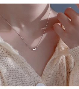 Close-up of S925 sterling silver bow pendant necklace on collarbone with snake chain