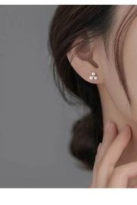 Détail de boucles d'oreilles fleur à trois perles en argent S925 sur l'oreille