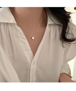 Close-up of minimalist S925 sterling silver cube necklace on model's neck collarbone