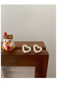 Macro shot of S925 sterling silver heart earrings with sparkling texture on a wooden stand