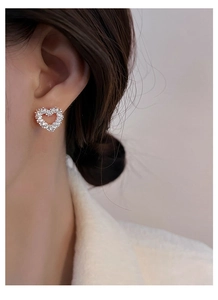 Detail view of heart shaped silver stud earrings with sparkling stones on model
