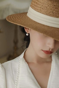 Détail d'une boucle d'oreille en argent S925 avec perle d'eau douce et crochet doré sur mannequin