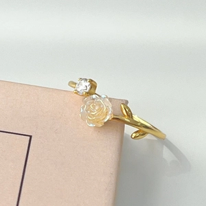 Macro detail of S925 silver camellia flower ring with gold vine band and zircon stone