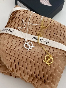 Close-up of gold and silver pretzel-shaped knot pendants on honeycombed paper wrap