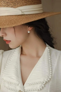 Détail d'une élégante boucle d'oreille en perles d'eau douce S925 portée dans un style français