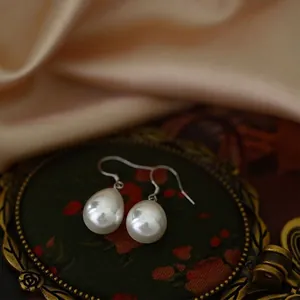 Elegant S925 sterling silver water drop pearl earrings displayed on vintage dark silk