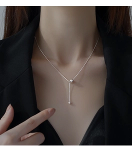Gros plan d'un collier lasso en argent S925 avec perles polies et chaîne élégante en Y