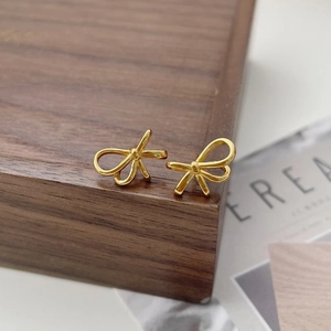 Detailaufnahme der goldenen Schleifen-Ohrstecker auf einer edlen Walnussholz-Box