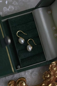 Détail des boucles d'oreilles en argent S925 et perles d'eau douce dans un écrin vert