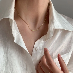 Minimalist S925 sterling silver golden bow pendant necklace worn on neck with white shirt