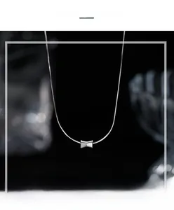 Macro shot of polished S925 sterling silver bow pendant on sleek snake chain
