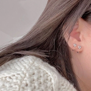 Gros plan de boucles d'oreilles cœur en argent S925 portées sur l'oreille d'un modèle