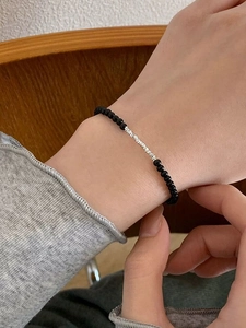 Detailed view of S925 silver and black onyx beaded bracelet worn on woman wrist