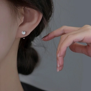 Vue rapprochée d'une boucle d'oreille cœur en argent S925 avec zircon portée à l'oreille