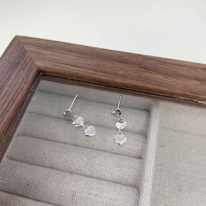 Détail macro de boucles d'oreilles triple cœur en argent S925 sur une boîte à bijoux