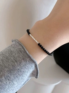 Macro detail of minimalist S925 sterling silver and black agate beaded bracelet on wrist