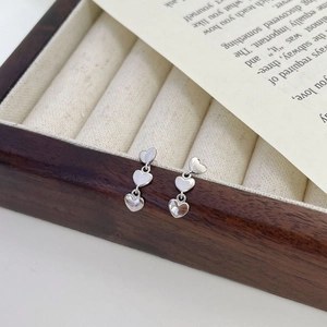 Détail de trois boucles d'oreilles en argent sterling en forme de cœur sur boîte en bois
