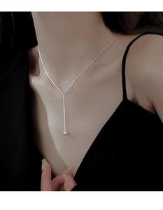 Detail of silver S925 Y-shaped tassel necklace with beads worn by a model in a suit