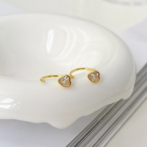 Détail de boucles d'oreilles cœur dorées minimalistes avec zircons sur un plateau
