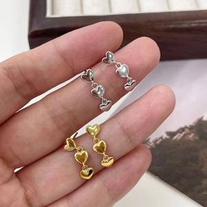 Gros plan de boucles d'oreilles en argent S925 avec trois cœurs en doré et argenté