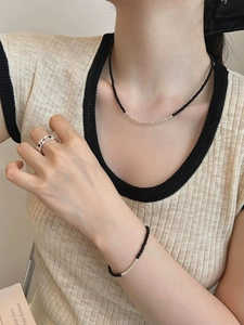 Close-up of a silver jewelry set featuring a black agate bead bracelet, necklace and wide ring