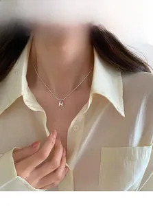 Gros plan du collier en argent S925 avec pendentif lettre H porté par un mannequin