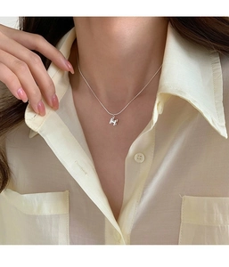 Gros plan du collier avec pendentif H en argent sterling S925 porté pour un style élégant