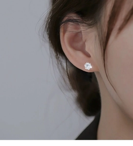 Macro shot of silver flower earrings with sparkling crystals worn on an elegant model