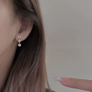 Détail de boucles d'oreilles pendantes à trois cœurs en argent sur l'oreille