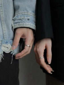 Close-up of minimalist S925 sterling silver frosted rings on a couple's hands