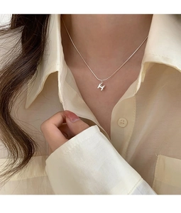 Gros plan d'un collier en argent sterling S925 avec pendentif H porté par un mannequin